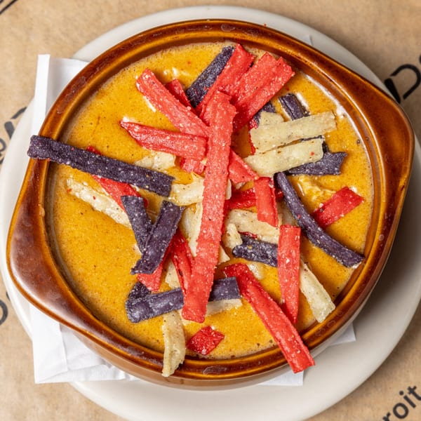 Top-down view of a bowl of CD Top Shelf queso dip with red, white, and blue tortilla strips.